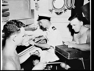 Officer and sailors doing the pay packets on HMAS Anzac...