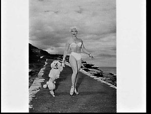 Woman in swimsuit with poodle on rocks
