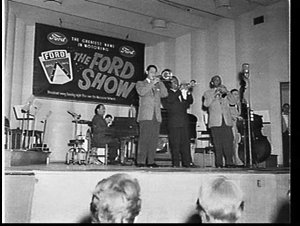 Louis Armstrong and his band playing before an audience...