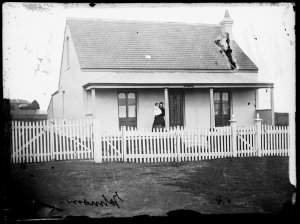 Woman and baby on the veranda of a single-storey, singl...
