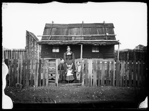 Mother and children at the front gate to a weatherboard...