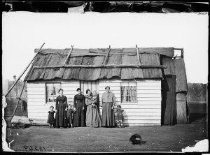 Women and children in front of a weatherboard house wit...