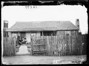 Woman with children, rocking horse and house, Hill End