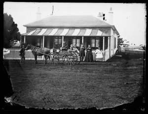 Family with horse and buggy in front of single-storey h...