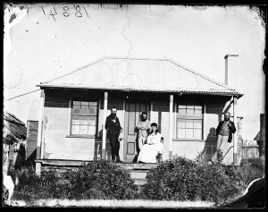 Three men and a woman on the veranda of a house, Hill E...