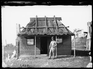 Portrait of man in suit and bowler hat in front of weat...