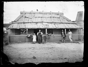 Bark roof, weatherboard house with men and children, Ta...