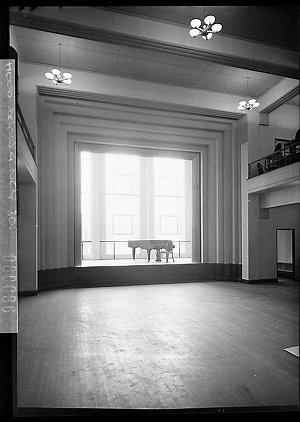 Interior of a hall showing a small stage with a grand p...