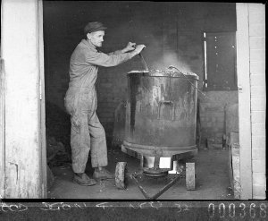 A workman batching a tank of paint