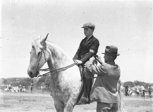 The judge ties the ribbon on arm of teenage horseman