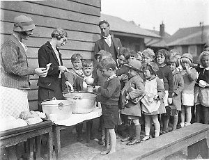 Schoolchildren line up for free issue of soup and a sli...