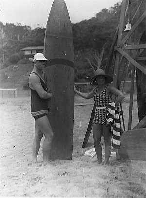 Man and woman with 9 foot wooden surfboard
