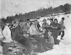 Group of skiers take refreshment in the snow; two Norwe...