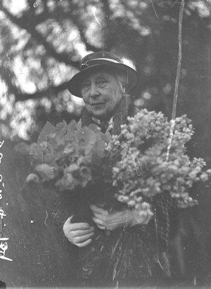 Woman with an armful of flowers at charity fair. Fete a...