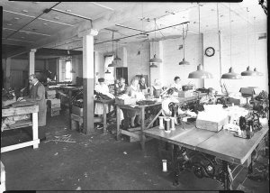 Workers in a clothing factory using power sewing machin...