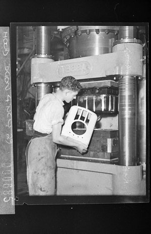 Factory worker takes moulded bakelite radio case from Nally Ware press (for Mingay Publishing Co)