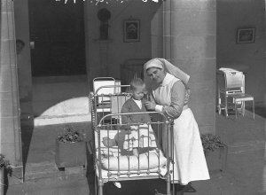 Nurse tends sick child in cot