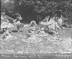 Nine students in colourful costumes dancing on the lawn