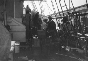 Q220: Loading ship at the wharf, Hobart (figure with the hat is Mawson) / Percy Gray