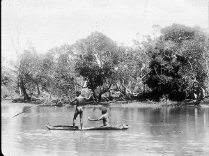 Two Aboriginal men spearing fish from canoe - Port Macq...