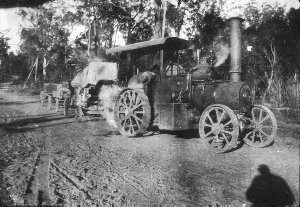 Traction engine with corn threshing equipment in tow. A...
