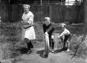 Bycroft children playing with hoop, tyre and wheel; the...