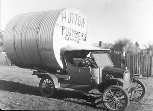 Jack Hutton, plumber, with water tank on the back of hi...