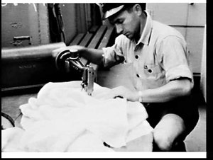 Yeoman N. Guthrie sews flag zeros on a Singer sewing ma...