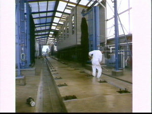 Workman waterproofing the concrete floor of the train w...