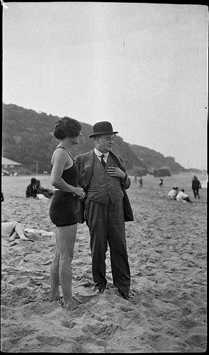 J.J. Rouse and woman in bathing costume, on a beach