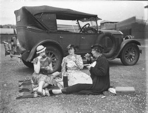 Three women cricket spectators picnicking beside a 1928...