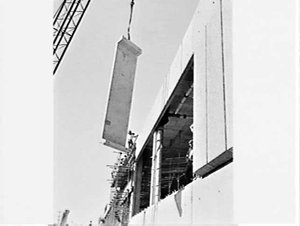 Crane hoists concrete wall panels into place on exterio...