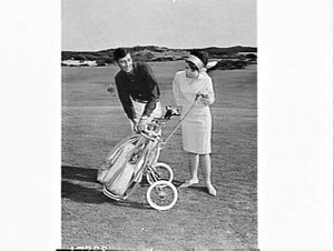 Male and female models with golf clubs, bag and buggy, ...