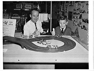 Man and boy play with Meccano Scalectrix model racing c...