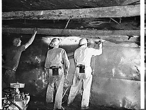 Spray painting latex rubber onto the wall of a coalmine, Coaldale