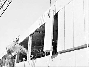 Crane hoists concrete wall panels into place on exterio...