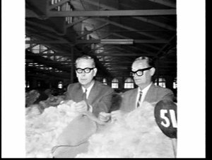 Manager and warehouse staff inspect wool, Farmers' & Gr...