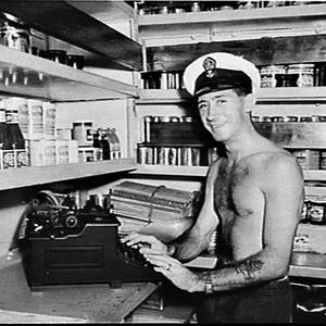 Sailor at a typewriter in the pantry on HMAS Warramunga...