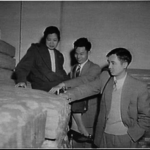 Asian students inspecting mattresses at a bedding facto...