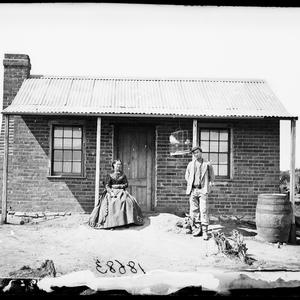 Man and woman in front of a brick house, Hill End