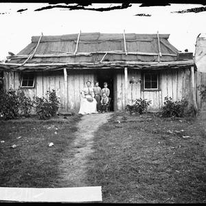 Woman and boys with slab hut house with bark roof, Hill...