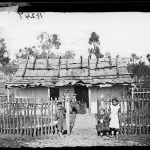 Family outside a slab house with bark roof, Gulgong