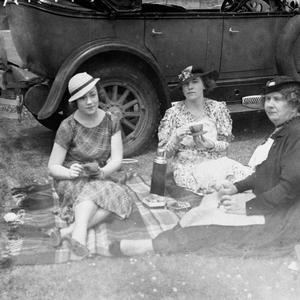 Three women having a picnic tea beside their 1927 Buick...