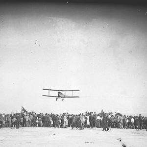 A Gypsy Moth flying low over the heads of spectators
