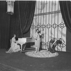Three women entertainers on stage; pianist, violinist, ...