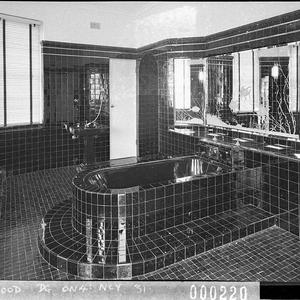 A view of a bathroom showing the raised black-tiled bat...