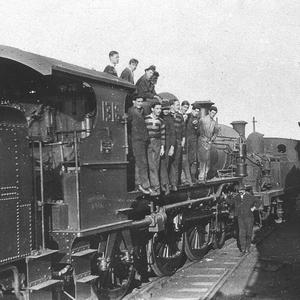 "Our mob on engine [no. 1318], foreman standing by pist...
