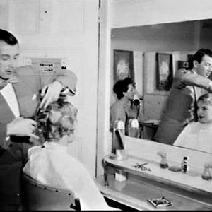 Hairdresser Mr. Stephan cutting a woman's hair, Rex Hot...
