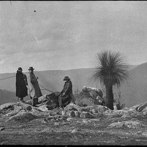 Perier party seated on a rocky outcrop, holding ropes