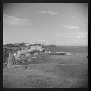 File 04: Caltex Story, La Perouse, shows aboriginal worker, Bare Island Fort, monument, old buildings, houses (shacks), ferry to Kurnell, Chevrolet car, mother and child (girl).  Sometimes known as Happy Valley, ca. 1953 / photographed by Max Dupain